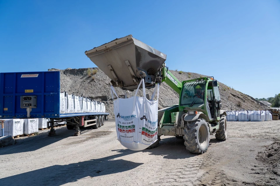 Manutention d’un big bag de granulats pour chargement sur camion au sein des carrières Malet.